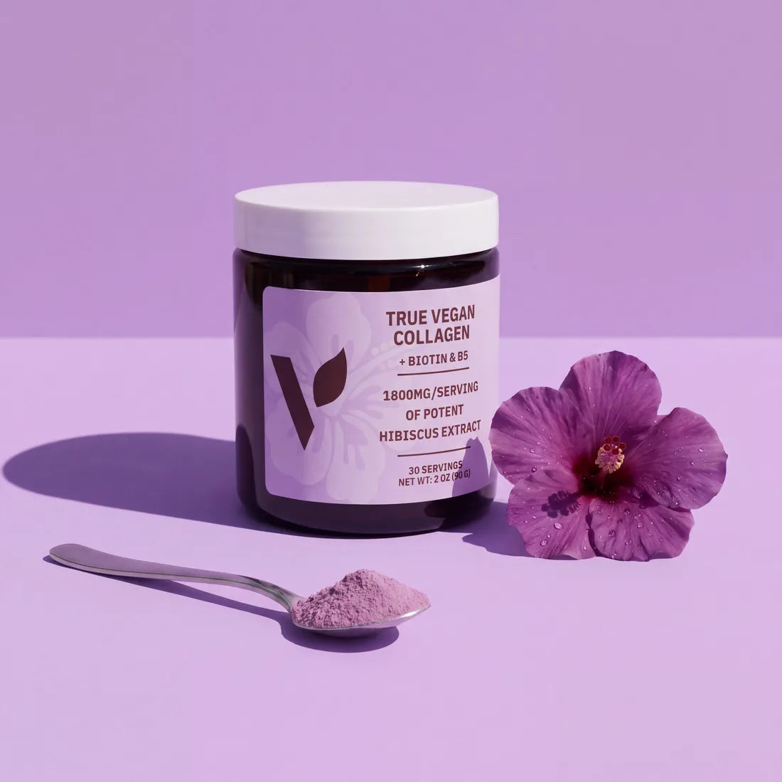 Jar of True Vegan Collagen on a lavender backdrop with a hibiscus flower and a spoon of powder