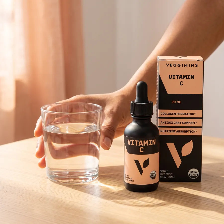 Hand reaching for a glass of water beside the Organic Vitamin C bottle and box